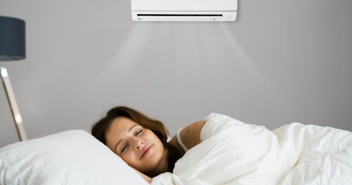 Een vrouw ligt vredig te slapen in een ruimte met een mobiele split airco die aan de wand bevestigd is.