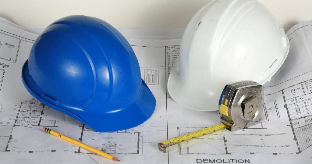 Een witte en blauwe helm op een bouwtekening voor het sloopopvolgingsplan.