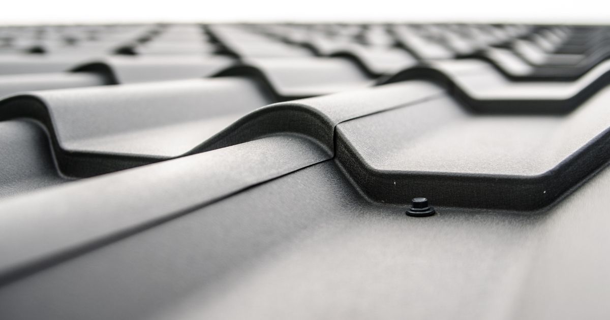 Close up van een dakpanplaat met zwarte kunststof 'dakpannen'.