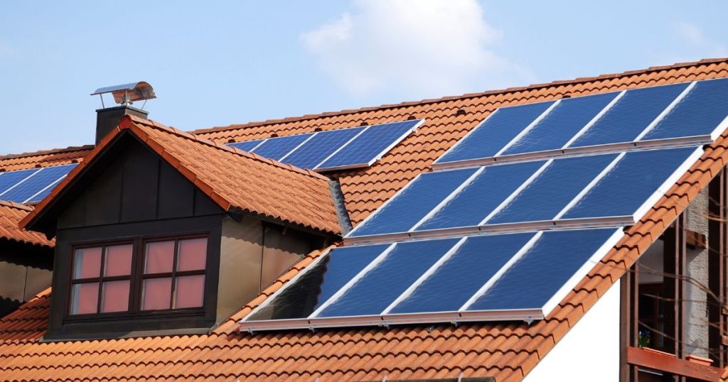 Een woning met een rood pannendak met zonnepanelen.