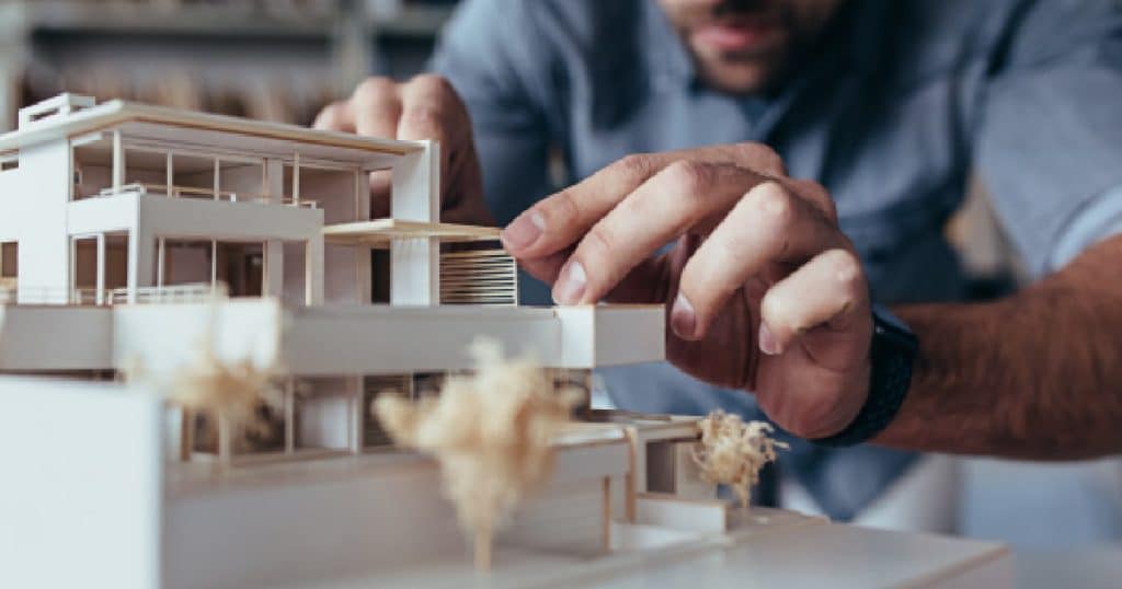 Een stabiliteitsingenieur gebruikt een maquette van een moderne woning als onderdeel van zijn stabiliteitsstudie.
