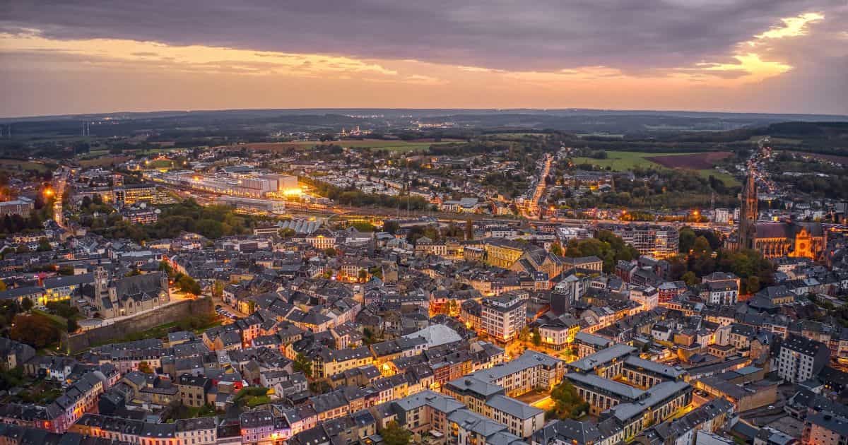 Arlon bij valavond vanuit de lucht bekeken: de wirwar van straten, rijwoningen en hoogbouw wisselen elkaar af, en veel straatverlichting.