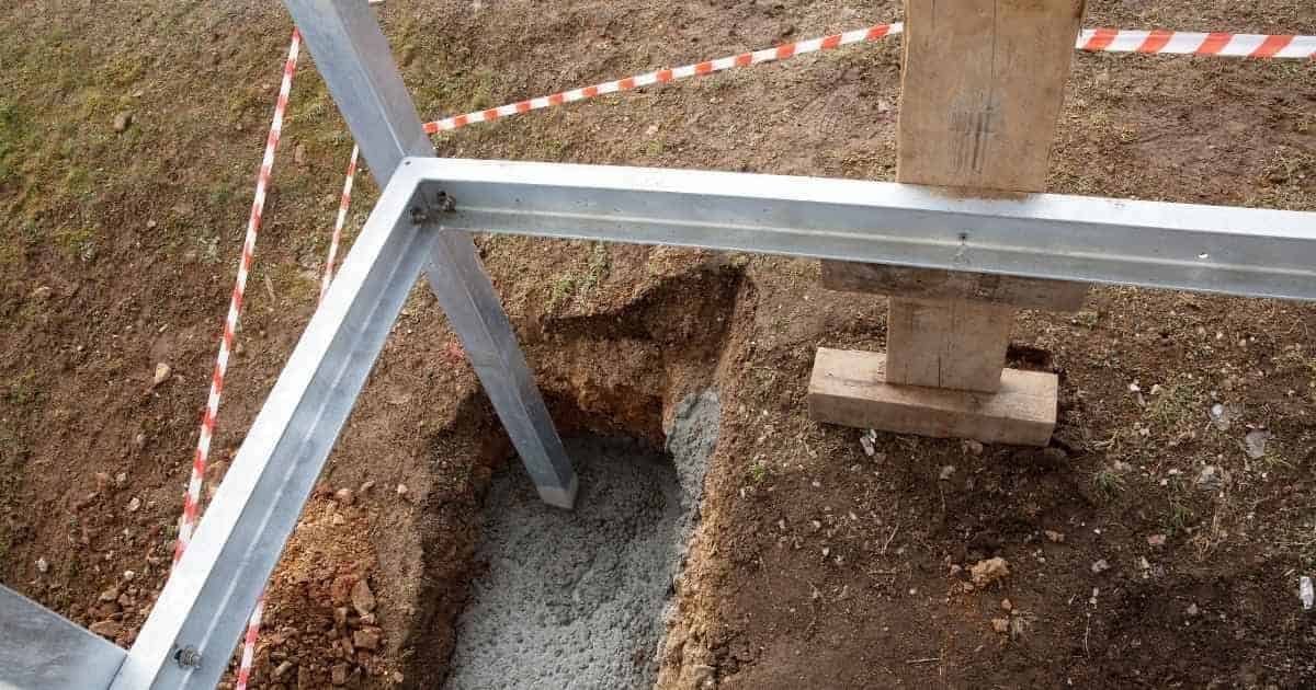 Een voorbereid stuk grond met fundering en metalen constructie, omringd door wit-met-rood lint.