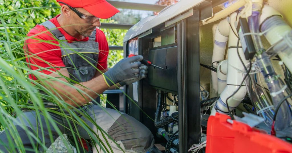 Technieker installeert een warmtepomp voor een jacuzzi in de tuin, met zicht op leidingen en pompinstallatie.