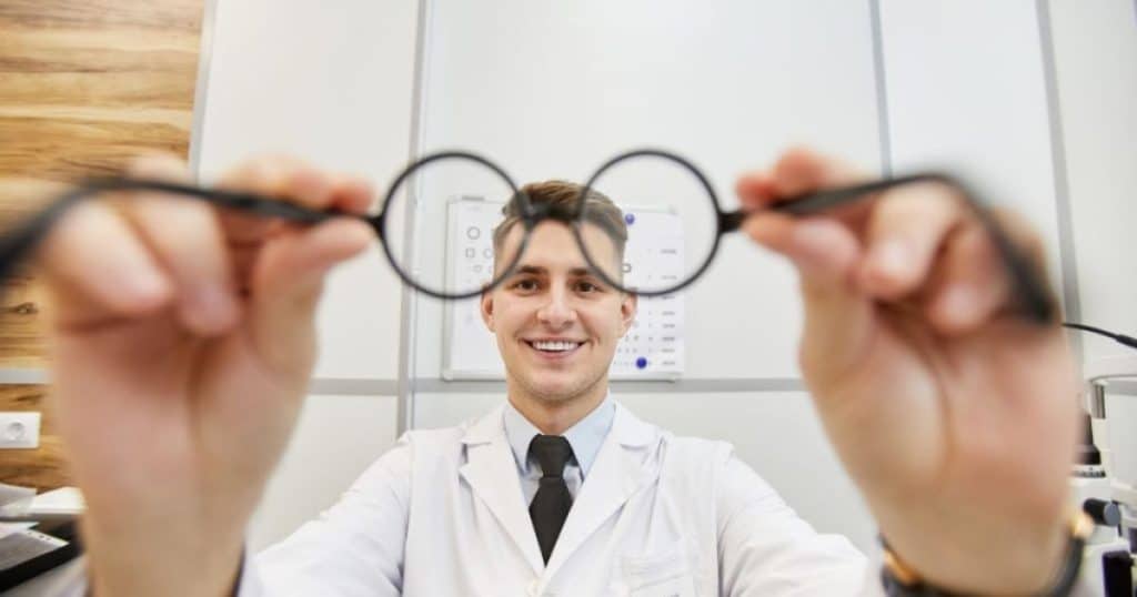 Een oogarts of opticien houdt en rond brilmontuur omhoog.