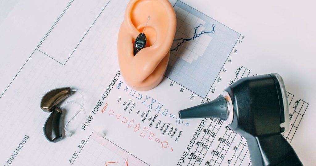 De tools van een audioloog of audicien: verschillende hoorapparaten op een blad met de resultaten van een gehoortest. 