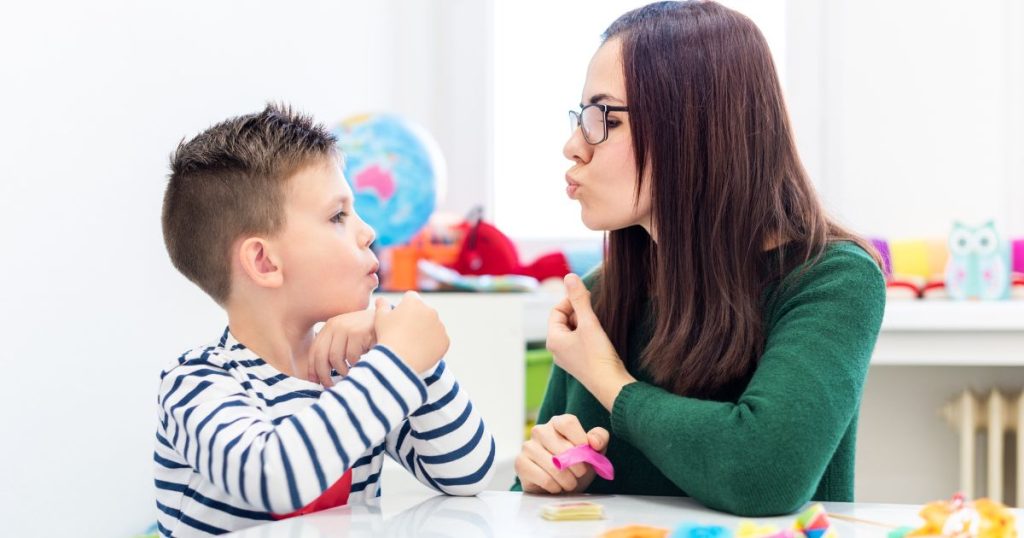 Een kinesist tuit de lippen. Haar jonge patiënt imiteert.