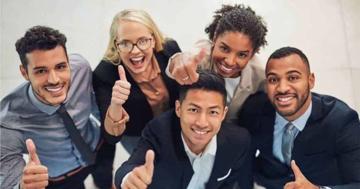 Tevreden zelfstandigen (3 mannen, 2 vrouwen) in maatpak kijken lachend naar de camera en houden hun duim omhoog.