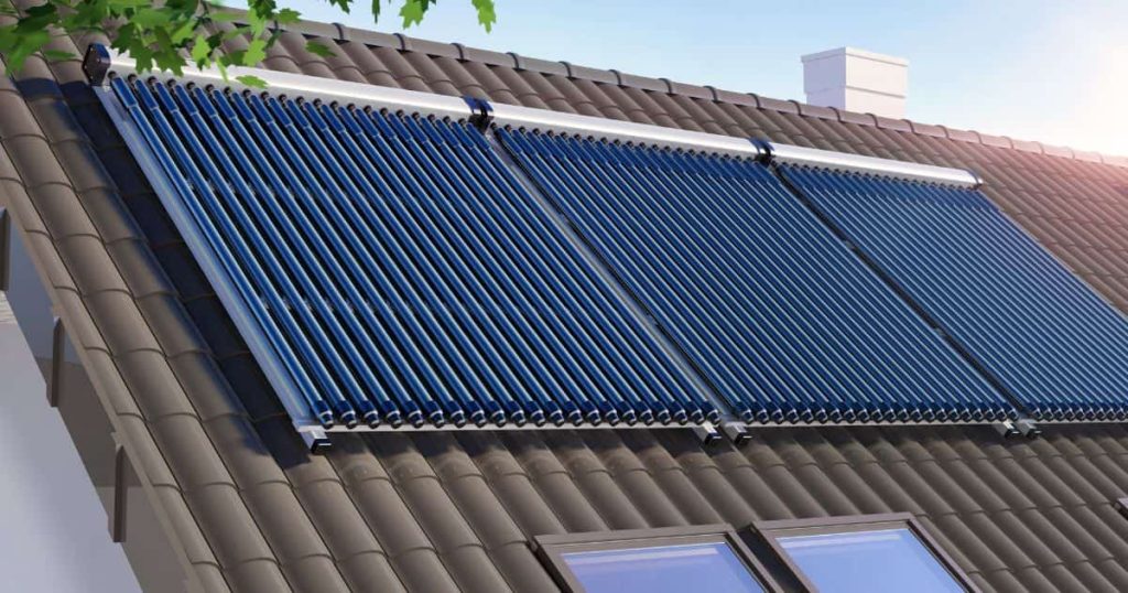 Op een grijs dak liggen drie grote thermische zonnepanelen. De zon schijnt fel vanaf de rechterkant