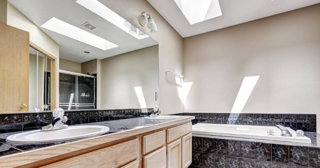 Een luxe badkamer met twee grote lichtstraten onder een plat dak.