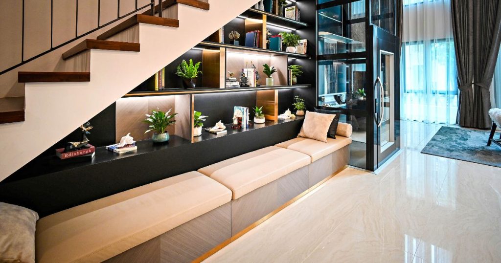 Een luxueuze witte trap met houten treden en zwarte leuning die men heeft laten opmeten of inmeten door een expert. Door de nauwkeurige metingen konden de bewoners van de woning de ruimte onder de trap optimaal benutten: een brede zetel en een ruime boekenkast maken van de ruimte onder de trap een volwaardige leefruimte.