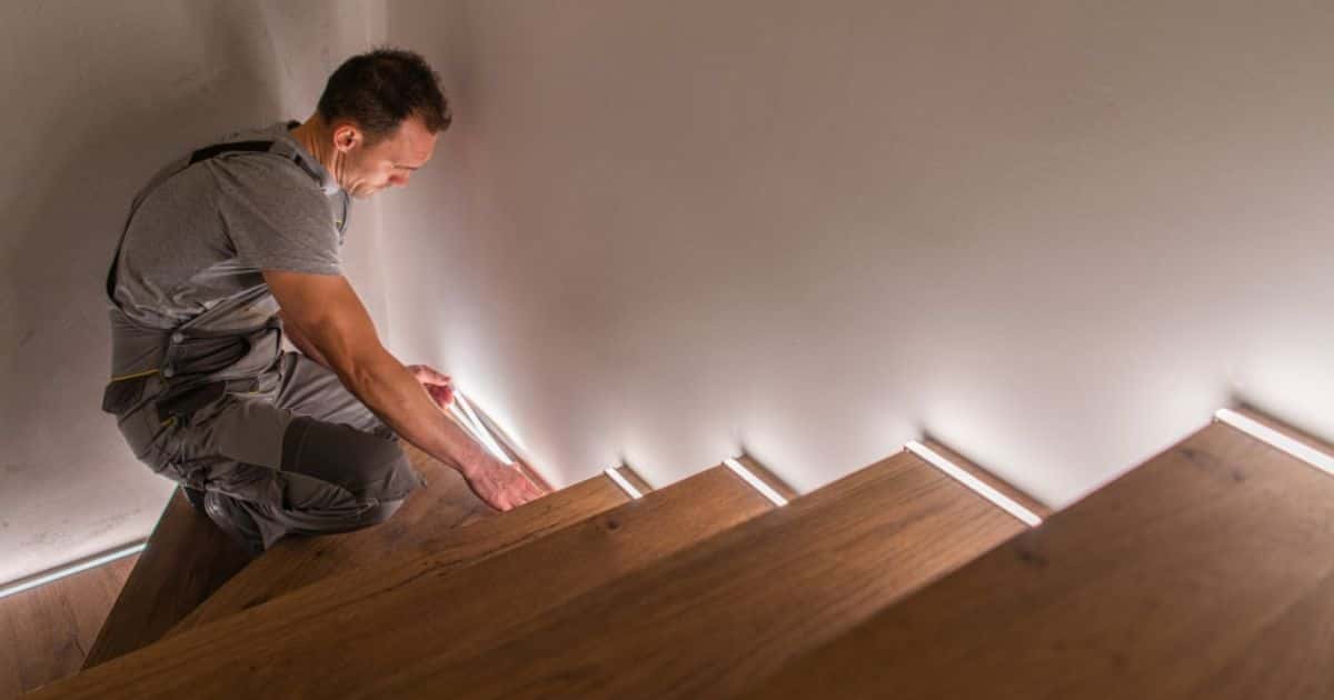 Een houten trap met ingebouwde verlichting behandeld met donkere beits.