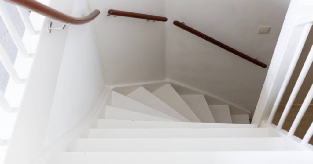 Dit is een witte trappengat met houten leuning. 