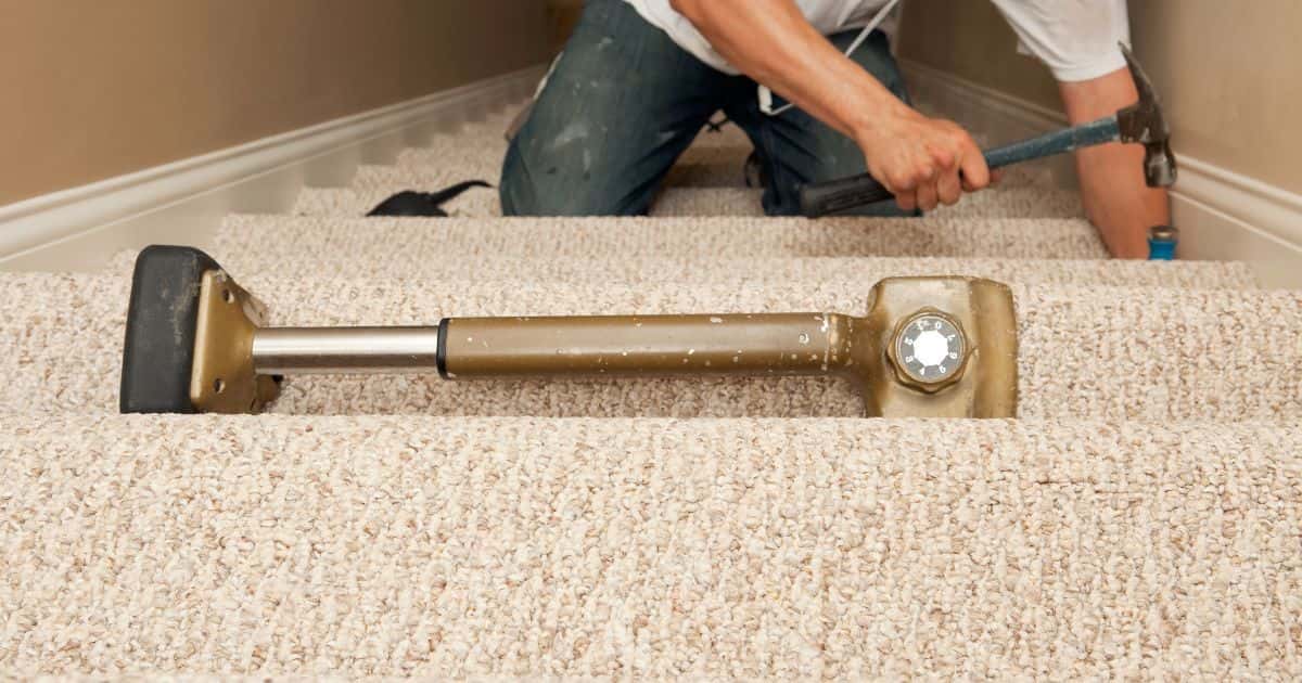 Een vakman bevestigt stoffen bekleding of traptapijt op een dichte rechte trap