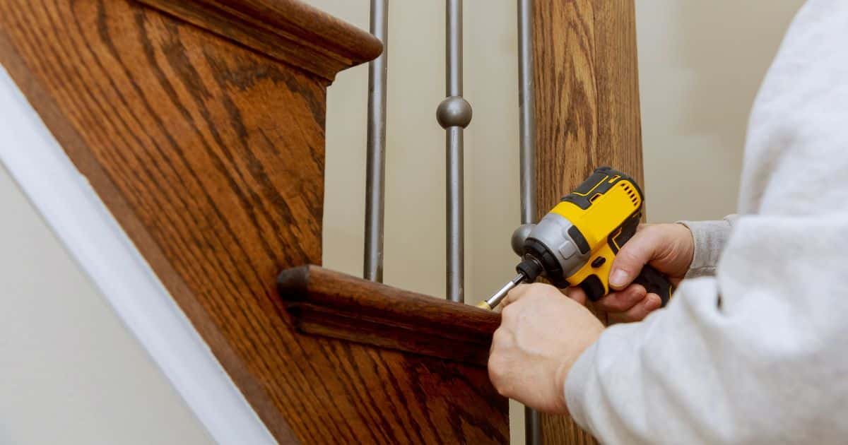 De spijlen van de trapleuning worden één per één vastgezet in de traptreden met een speciaal schroefboortoestel.