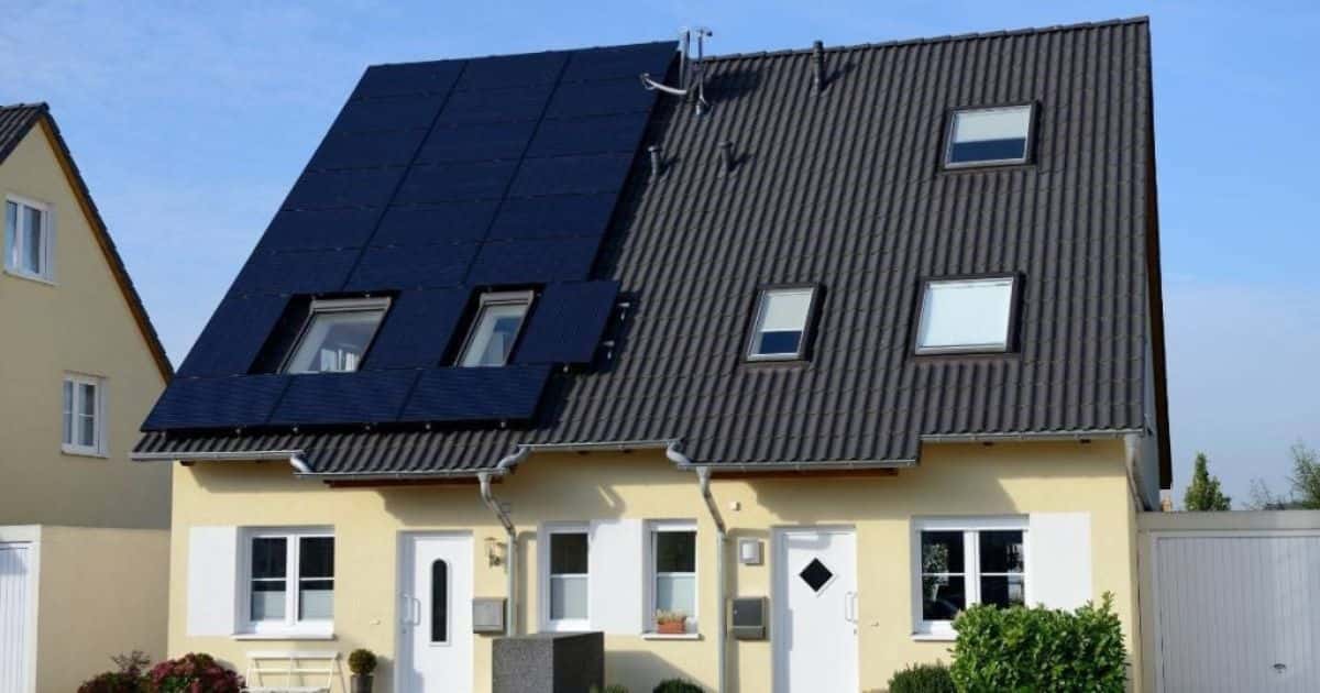 Twee moderne woningen met gele gevels en een steil hellend dak. Het linkse huis beschikt over een grote zonnepaneelinstallatie.