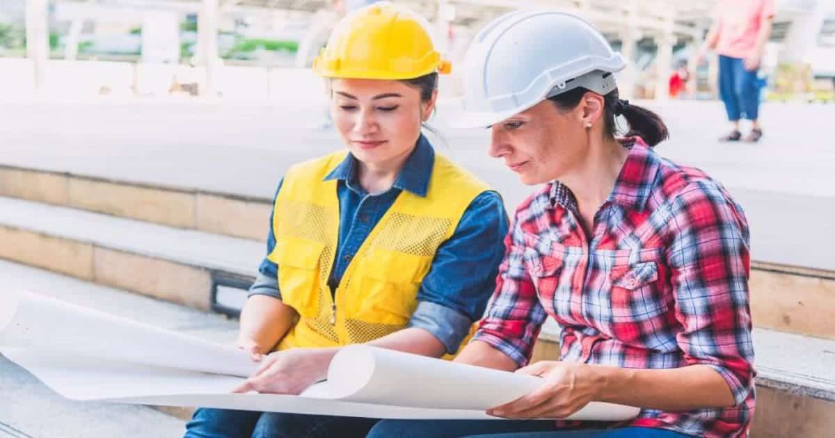Twee personen met veiligheidshelmen die samen bouwplannen bekijken