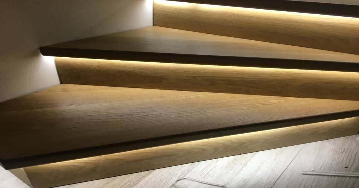 Een unieke houten trap met ledverlichting onder de treden als afwerking.