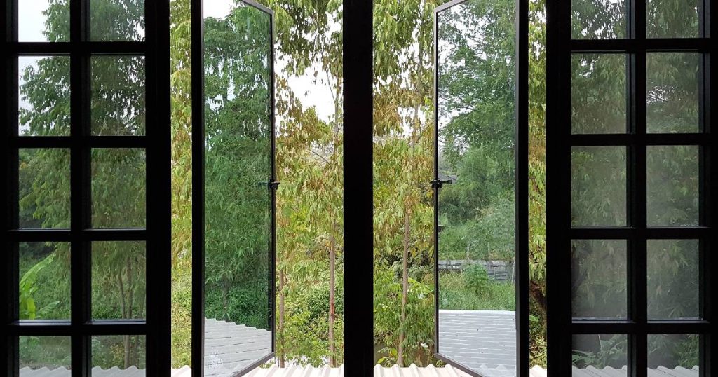 Vooraanzicht van twee deuren met schuif-draaisysteem van glas en aluminium waarmee men een veranda heeft laten dichtmaken.
