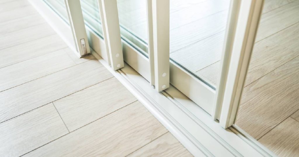 Schuin bovenaanzicht van een schuifwand met drie rails op een licht houten vloer.
