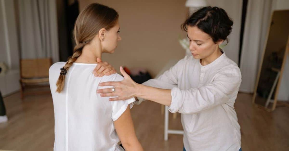 Een haptotherapeut behandelt de schouder van een patiënt.