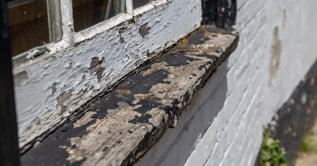 Een verouderd of verloederd kozijn van een venster dat dringend wat opfrissingswerk kan gebruiken.