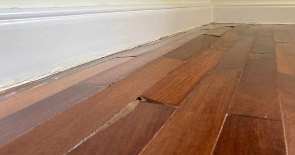 Houten vloer met opbollende en beschadigde planken door vocht