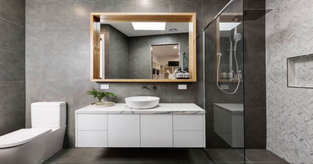 Moderne gerenoveerde badkamer met hangtoilet, zwevend badkamermeubel, inloopdouche en grote spiegel met houten omlijsting