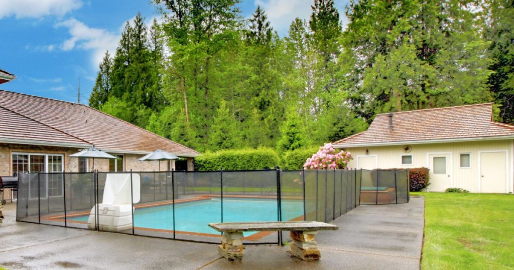 Een tuinveranda die fungeert als poolhouse naast een zwembad in een groene tuin.
