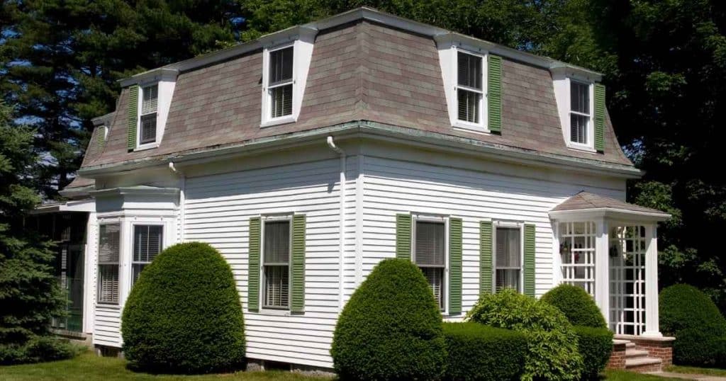 Een vrijstaande woning met mansardedak met verschillende dakkapellen.