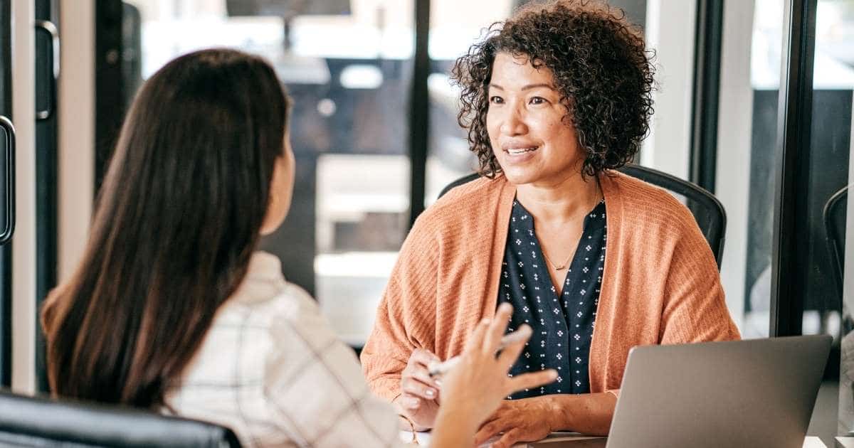 Een medewerkerster in gesprek met een adviseur over loonkostenberekening en personeelsadministratie bij een sociaal secretariaat.
