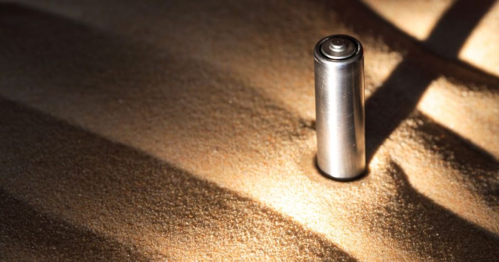 Een batterij in golvend zand, met een lange schaduw dankzij de dramatische belichting.