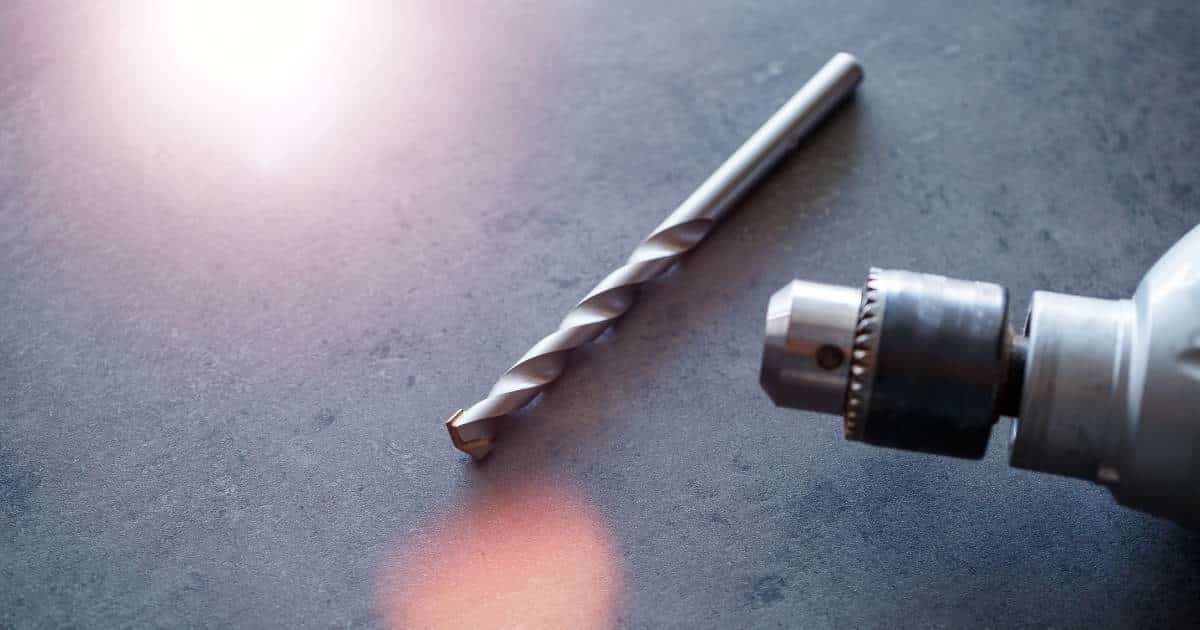 Close-up van een betonboor en opzetstuk op een gepolijste betonnen vloer.