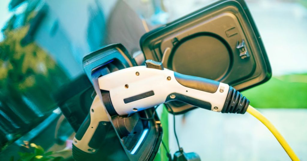 Close-up van een wit met zwarte laadkabel in de plug van een elektrische auto.