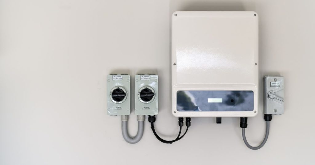 Een witte thuisbatterij hangt aan een witte muur.
