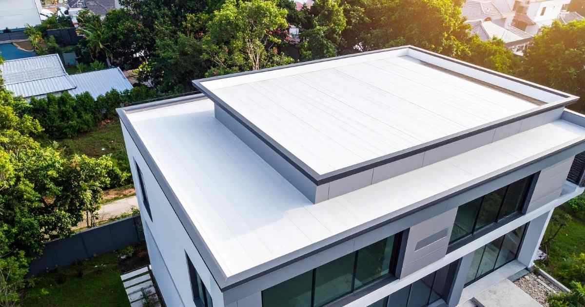 Een modern gebouw met een plat dak bestaande uit 2 platformen. Het dak is bedekt met witte pvc dakbedekking. Het gebouw beschikt over een tuin met gras en ligt in een vrij groene omgeving.