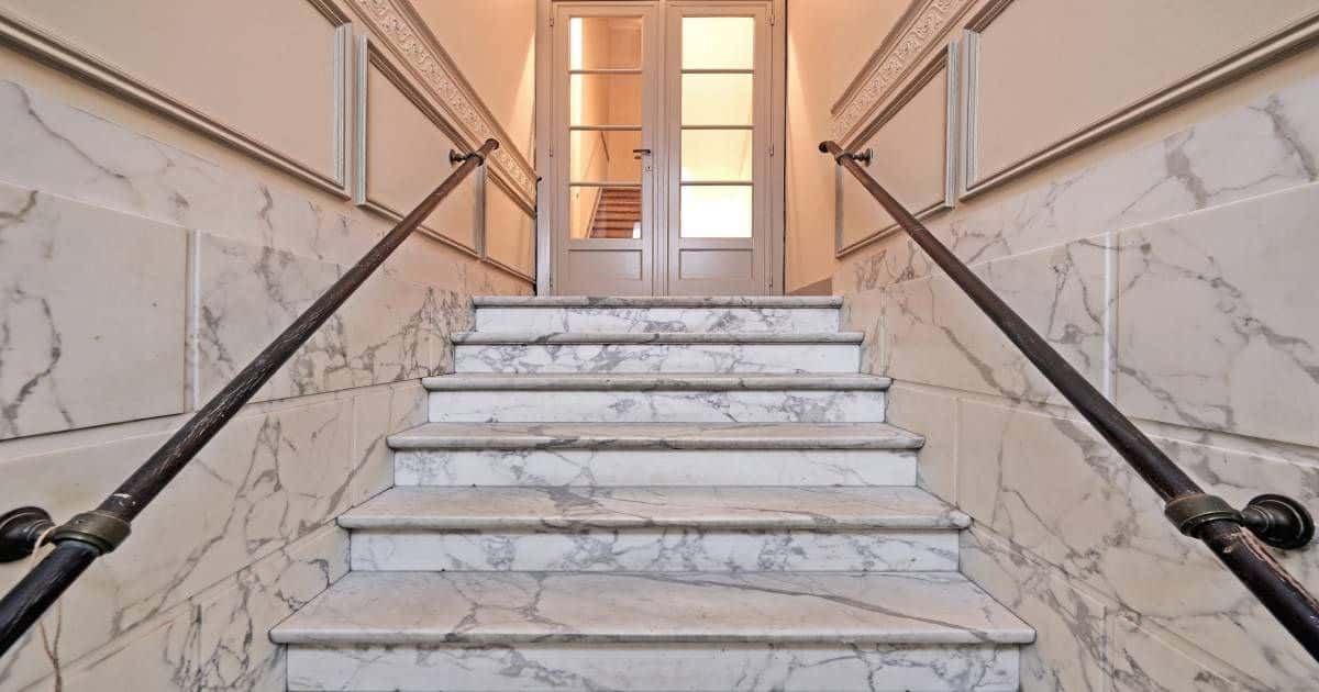 Marmeren overzettreden en een metalen trapleuning in een vrij klassiek ogend interieur.