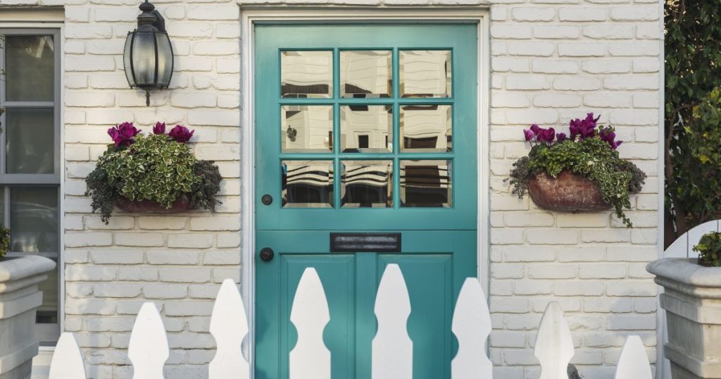 Witte gevel met crepi in baksteenmotief en blauwe deur