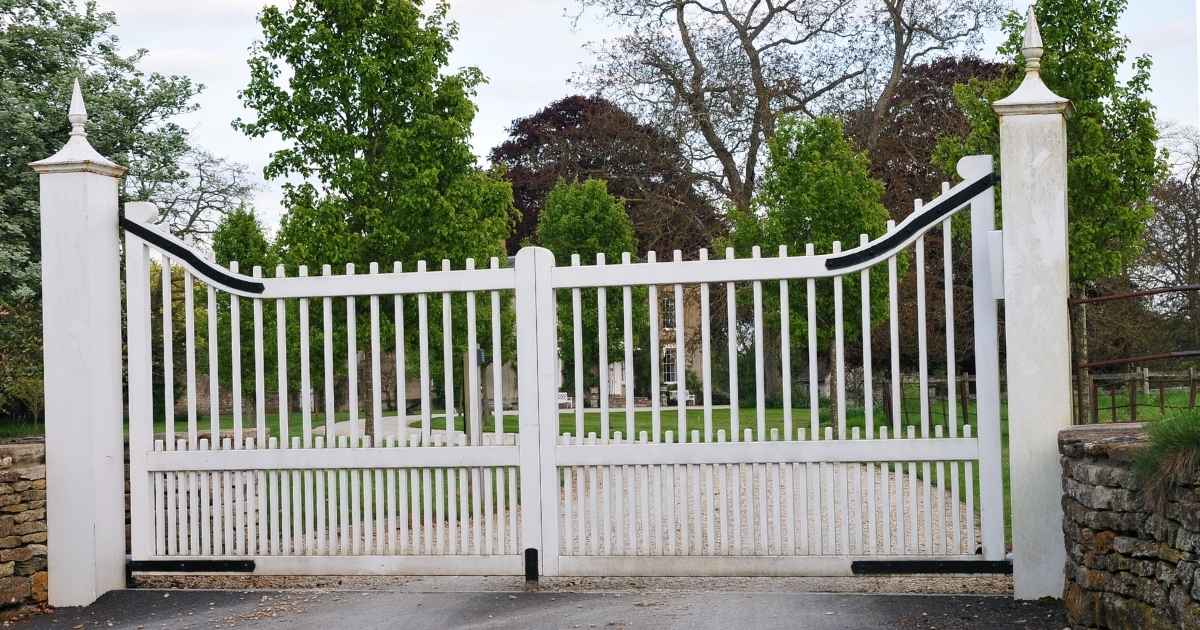 Een witte, metalen dubbele draaipoort met spijlen. 