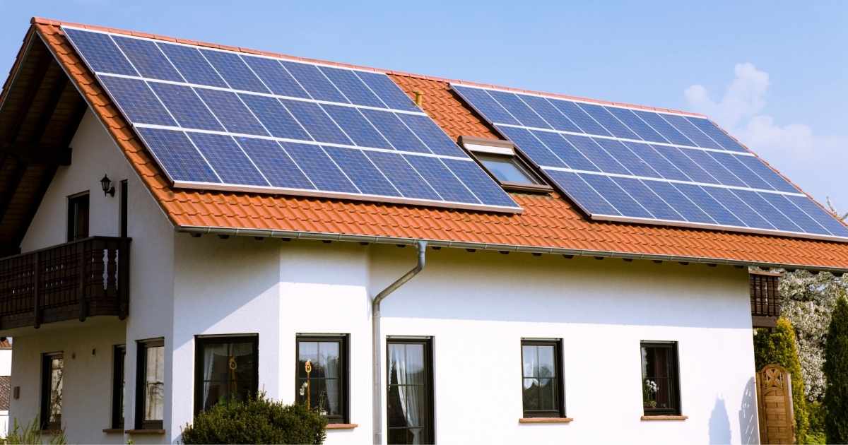 Een woning met witte gevels en een zadeldak. Op het zadeldak ligt een ruime zonnepaneelinstallatie. Het dak is voorts afgewerkt met rode dakpannen, en voorzien van een lein dakraam.