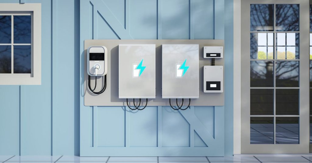 Een installatie van 2 thuisbatterijen met omvormer tegen een blauwe houten wand. Links ervan is ook een laadpaal geïnstalleerd.