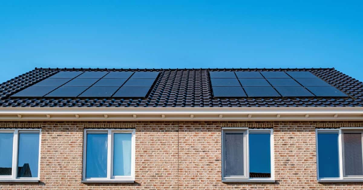 Twee aan elkaar grenzende huizen met  schuin dak en een grote zonnepanelen installatie.