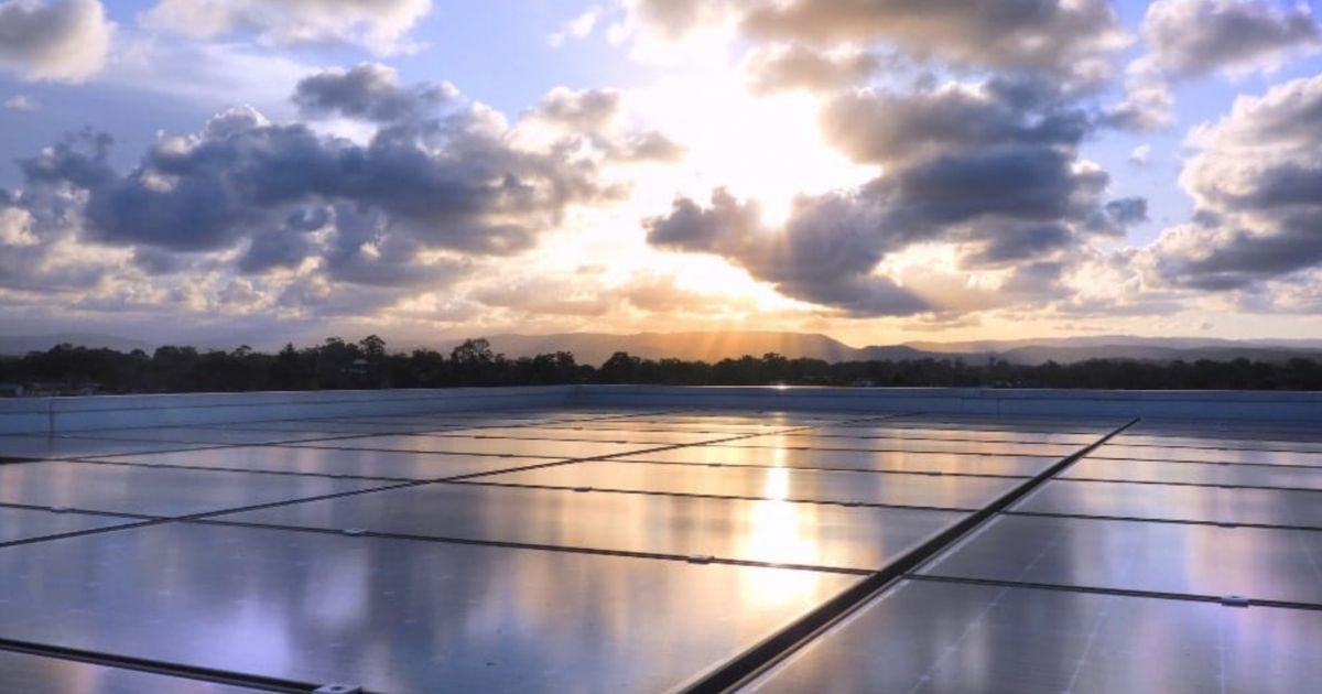 Een plat dak met zonnepanelen waar de zon op schijnt