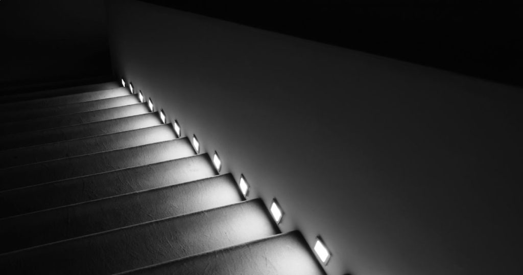 Mooie zwarte trap met ledverlichting in de muur boven elke trede.
