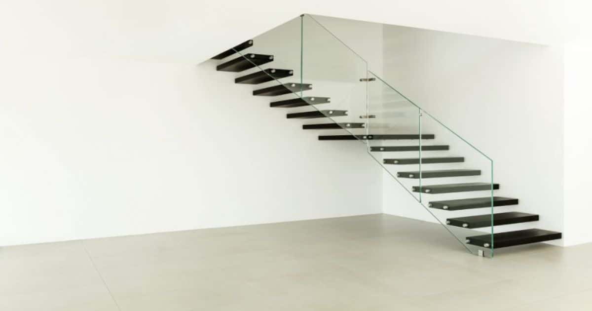 Een zwevende, open trap met betonlook treden en glazen leuning. 