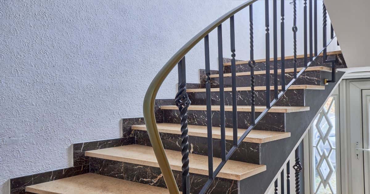 Een zwarte trap met bruine treden en een metalen trapleuning.