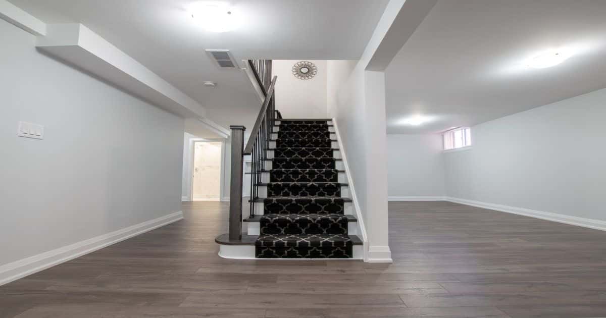 Donkere traploper met een motief. Traploper ligt op een witte trap met donkerbruine treden en leuning. Gelegen in een grote witte ruimte. De ruimte staat leeg.