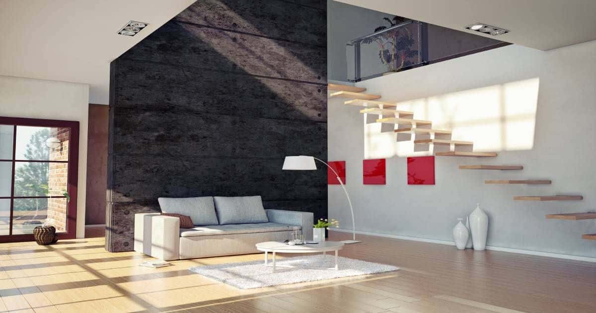 Zwevende trap in een woonkamer. Onder de zwevende trap hangen 3 rode schilderijen en staan 3 witte vazen. Er is ook een grote zwarte muur aanwezig in de woonkamer. 